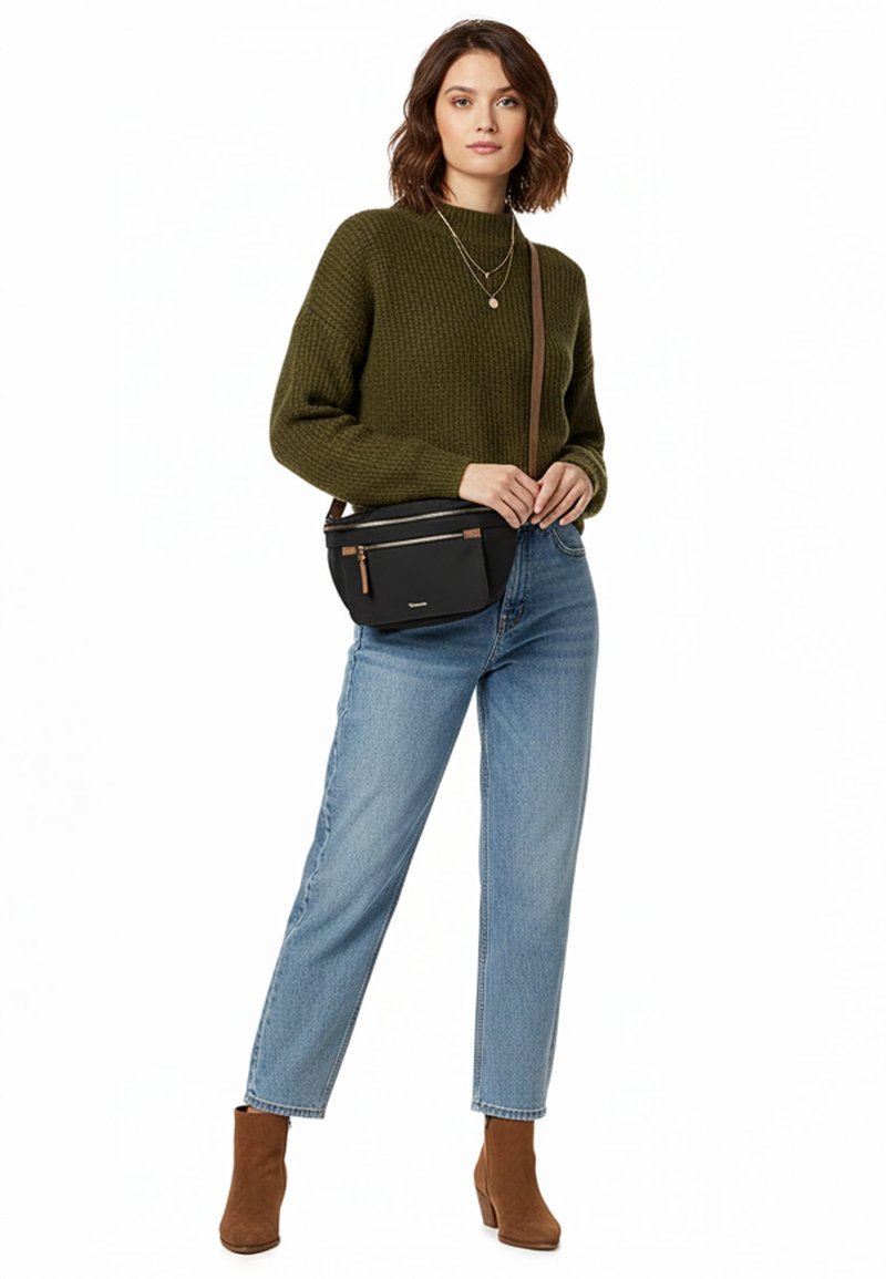 Naine kannab oliivrohelist kootud kampsunit, helesiniseid teksapükse, pruune pahkluu saapaid, mitme keti kaelakeesid ja musta õlakotti esist luku taskutega.