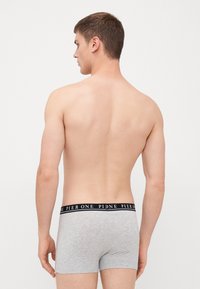 Boxeri gri cu un brâu negru, având text alb. Modelul este văzut din spate, evidențiind croiul și designul.