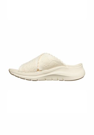 Witte instap sandaal met textuurgebreide gekruiste bandjes en een gevoerde zool, zijaanzicht tegen een effen achtergrond.