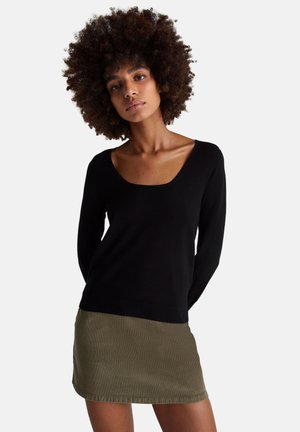 Černý svetr s výstřihem do U a dlouhými rukávy, spárovaný s olivově zelenou minisukní. Texturovaná látka s přiléhavým střihem.