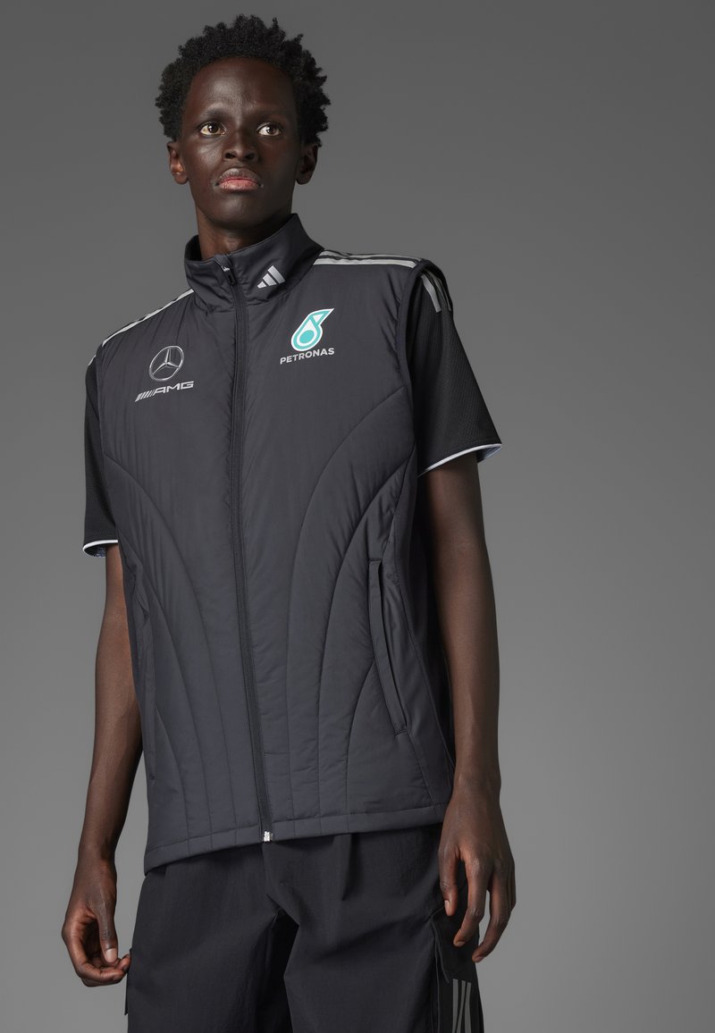 Sort polstret vest med lynlås, der har hvide accenter og logoer. Ærmeløst design med tekstureret stof og sidelommer.