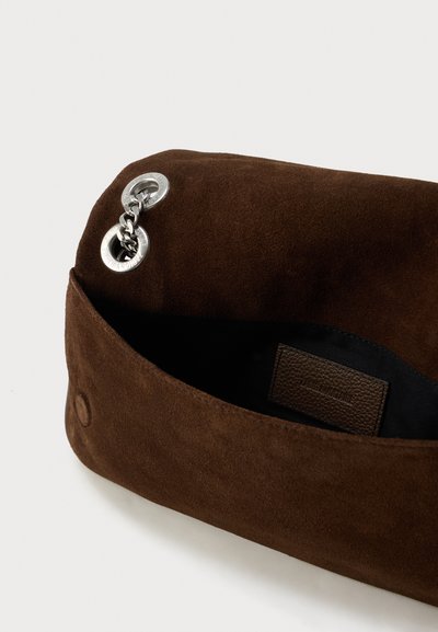 Barna velúr borítéktáska fém szemmel és lánc részlettel. Belsejében sötét bélés és texturált címkepárna található.