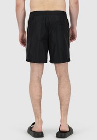 Pantaloni da bagno neri con vita elastica e tasche laterali, caratterizzati da una texture liscia e un design minimalista. Nessun motivo o dettaglio visibile.