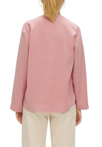 Lichtroze, langemouwen T-shirt met ronde hals van katoen. Heeft een relaxte pasvorm met een afgeronde zoom en zij-splitten voor gemakkelijke beweging.