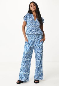 Set coordinato con motivo blu e bianco, composto da una camicia collare a maniche corte e pantaloni a gamba larga, realizzati in tessuto leggero.