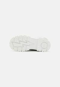 White sneaker sole with textured rubber patterns, featuring an angular lightning bolt design and a circular logo at the heel.