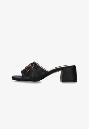 Sandali con tacco in pelle nera con una fascia larga e un dettaglio in fibbia dorata, progettati per essere indossati facilmente.