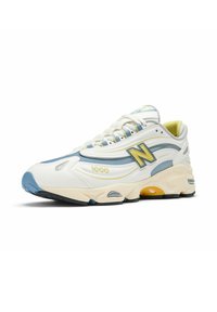 New Balance 1000 -kengät, joissa on valkoinen, sininen ja keltainen muotoilu, teksturoitu päällinen, pehmustettu pohja ja silmiinpistävä logo sivussa.