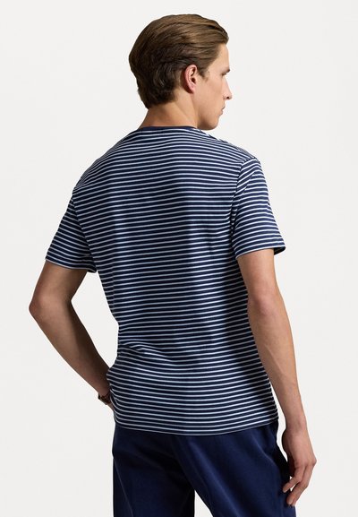 Jūrinės ir baltos dryžuotos medvilninės marškinėlių su trumpomis rankovėmis, apvaliu iškirpimu ir laisvu siluetu. Atgalinės pusės vaizdas rodo lygius dryžius ir švelnų tekstūrą.