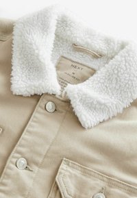Beige skjortejakke med en blød hvid faux shearling krave, frontknapper og brystlommer. Etiketten angiver normal pasform, størrelse M.