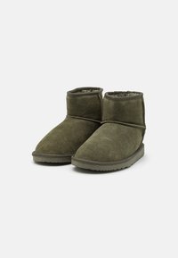 Bottes courtes en daim vert avec intérieur doux et texturé, bout arrondi et semelle en caoutchouc plate. Présentent un design à coupe basse et des coutures minimales.