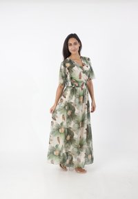 Abito maxi con un motivo floreale verde e beige, maniche corte a volant, scollatura a V e vita elastica per una vestibilità fluida.