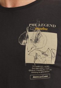 Camiseta de algodón negra con un gráfico crema de un avión de carga y texto que incluye "PME Legend" y "American Classic".