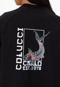 Černá mikina s bílým grafickým designem z karpu koi, textem "COLUCCI", "CARLO" a "EST. 1978" v červené a bílé barvě.
