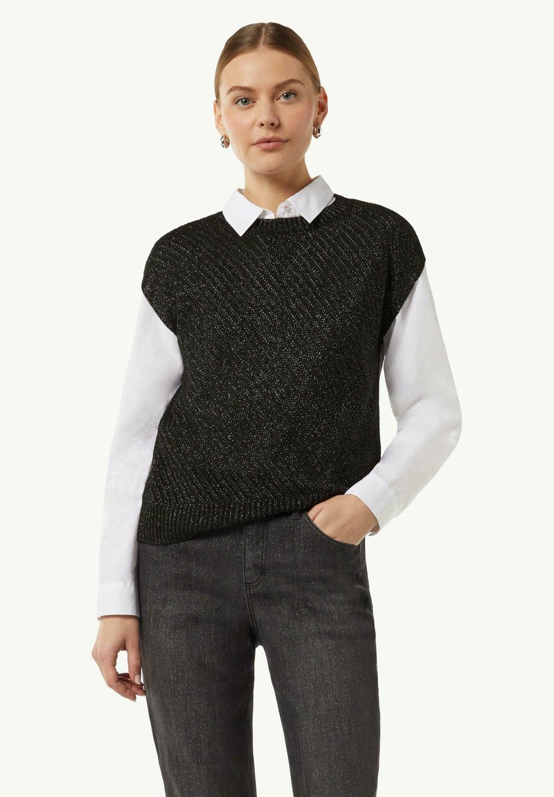 Czarny dzianinowy kamizelka z teksturowanym wzorem, noszona na białej koszuli z kołnierzykiem, w połączeniu z ciemnymi dżinsami.