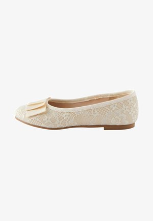 Ballerine in pizzo color crema con un accento a fiocco. Presenta una punta rotonda e una suola sottile e piatta. Una sovrapposizione di pizzo testurizzato copre tutta la parte superiore.