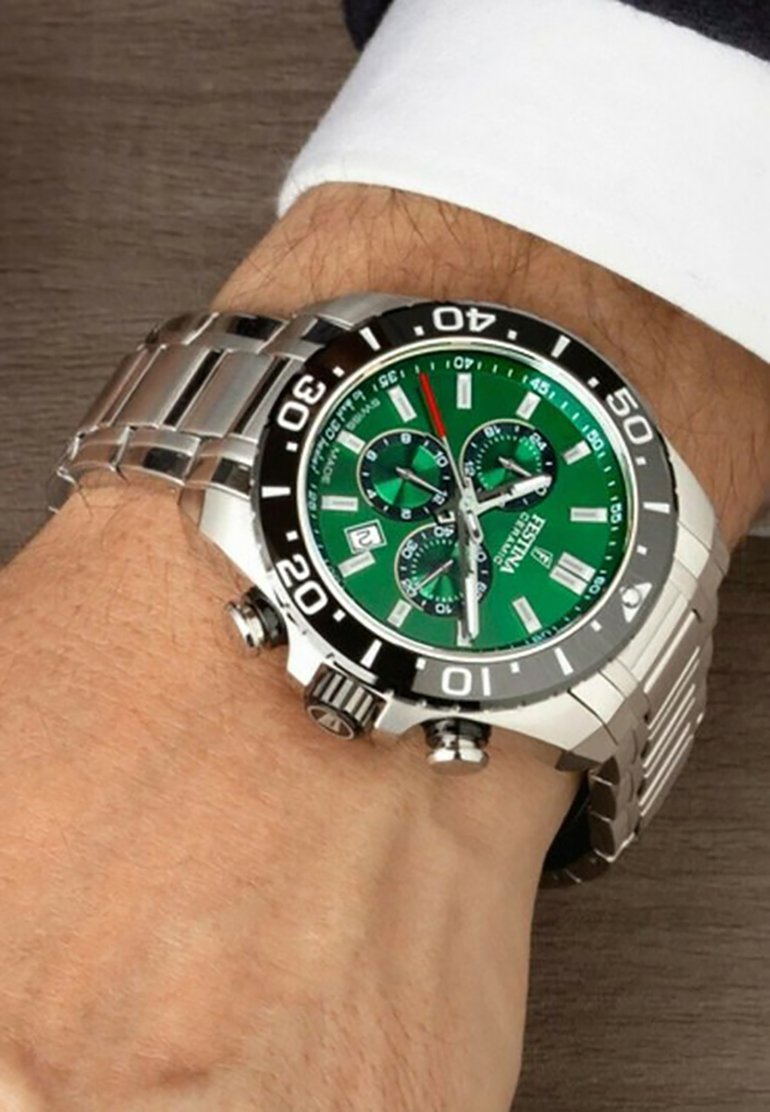 Orologio in acciaio inox con quadrante verde, lunetta nera e bracciale argentato. Presenta tre sottodial e una visualizzazione della data alle 4.
