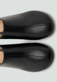 Zapatos negros de piel sin cordones con una textura suave, puntera redondeada y un diseño minimalista. Sin herrajes ni patrones visibles.