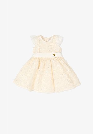 Kremowa, bezrękawnikowa sukienka dla niemowląt z kwiatową koronką typu ażurowego, falbankami na ramionach oraz białym pasem w talii ozdobionym małym złotym serduszkiem.