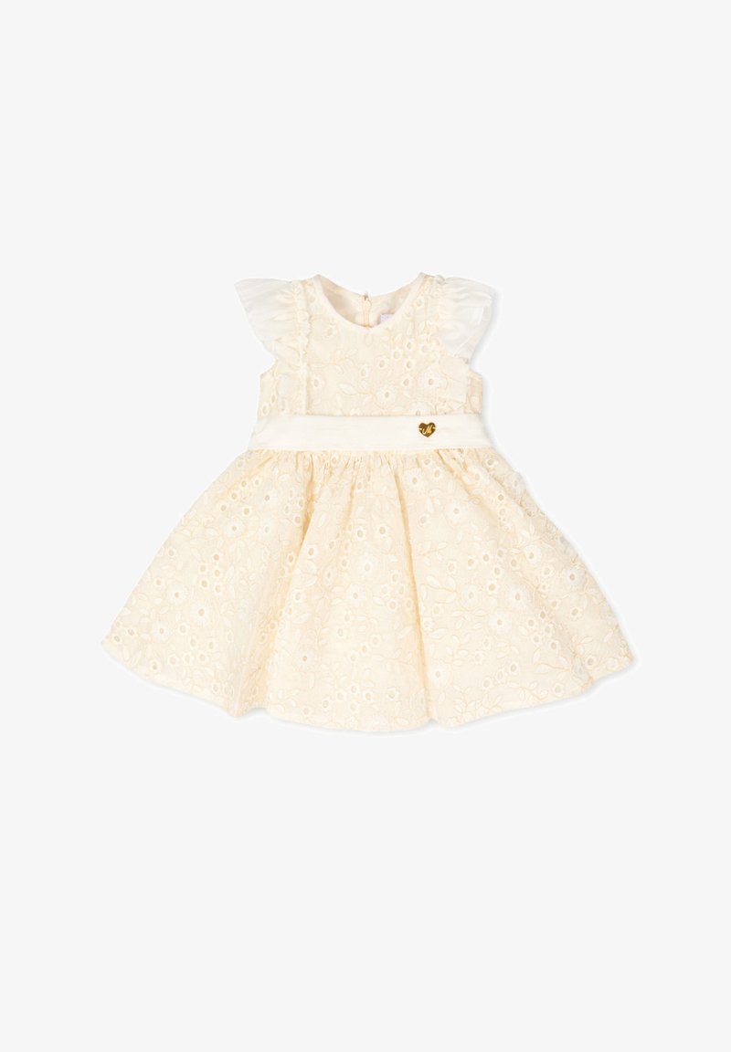 Vestido de bebé sin mangas color crema con encaje de ojales floral, hombros con volantes y una cintura blanca con un pequeño colgante de corazón dorado.