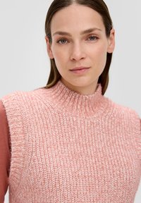 Rosa gestrickter ärmelloser Pullover mit einem gerippten hohen Kragen. Der Stoff hat eine weiche Textur und ein gemischtes Muster, das hellere und dunklere Garne umfasst.