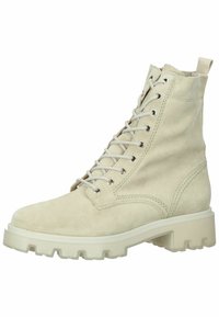 Stivale alla caviglia in suede beige con lacci, suola spessa a rilievo e linguetta, caratterizzato da cuciture dettagliate e occhielli in metallo.