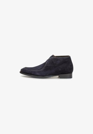 Bottines en suède bleu marine avec un bout arrondi, un laçage à l'avant et un petit talon noir. Texture lisse avec un subtil détail de couture.
