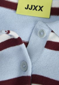 Bomulds polo T-shirt med lyseblå bund, maroon og hvide striber, to grå knapper og et gult mærke med "JJXX" i sort tekst.