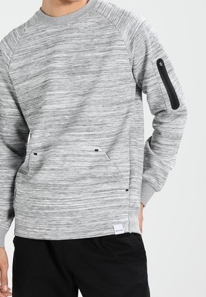 Grau strukturierter Sweatshirt mit Raglanärmeln, ausgestattet mit zwei vorderen Taschen und einer mit Reißverschluss versehenen Armtasche mit schwarzen Hardwareakzenten.