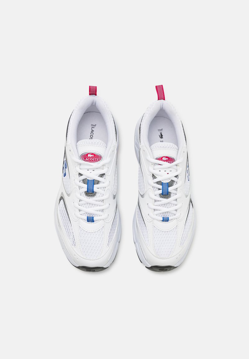 Baskets de sport blanches avec des panneaux en mesh, accents bleu et rose, système de laçage, semelle rembourrée et logo Lacoste sur le côté.