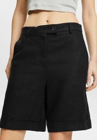 Zwarte shorts van een lichtgewicht stof, met een rechte snit, zijzakken, een knoopsluiting aan de voorkant en omgeslagen manchetten.
