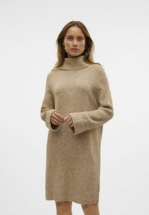 Robe col roulé beige en tissu doux et texturé, avec des manches longues à larges poignets côtelés et une silhouette décontractée.