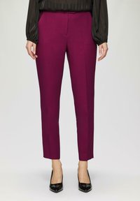 Pantalons ajustés magenta avec une coupe slim, dotés d'un devant plat, de poches latérales et d'une texture de tissu lisse.