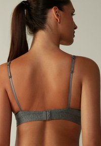 Sostenedor gris con tirantes finos y un cierre simple en la parte posterior, hecho de un material suave con una textura lisa y costuras mínimas.