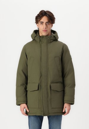 Giacca parka verde oliva con cappuccio, dotata di zip e chiusura a scatto, due tasche frontali e una consistenza spessa e isolante.