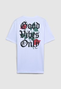 Biała, oversize t-shirt z czarnym napisem "Good Vibes Only" i czerwonymi różami na plecach. Wykonana z miękkiej bawełny o gładkiej teksturze.