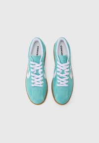 Turkise ruskindsneakers med hvide snørebånd, prydet med hvide sideaksenter og gummisåler, der fremviser et klassisk atletisk design.