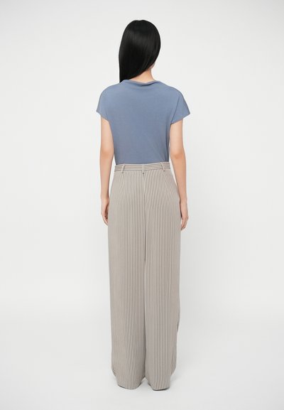 Szary T-shirt i beżowe, w kratkę, szerokie spodnie. Miękka tkanina, luźny fason, z delikatną teksturą i wysokim stanem. Pionowe paski na spodniach.