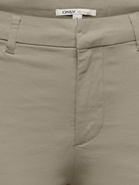 Pantalon beige taille haute avec passants de ceinture et fermeture éclair avant dissimulée, présentant une petite étiquette avec le nom de la marque et la taille S.