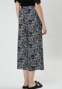 Zwart-witte geblokte wijde broek met een elastische tailleband, een gladde textuur en een cropped lengte, met abstracte ontwerpelementen.