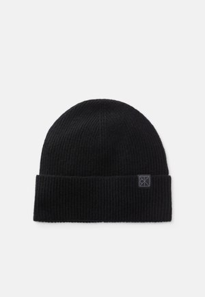Must näiliselt must ribakai tikkimisest valmistatud beanie, millel on volditud ääreosa. Ees on väike ristkülikukujuline logo silt.