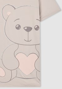 Camicetta beige chiaro con una grande grafica di un orsetto di peluche che tiene un cuore rosa contornato di glitter argentato sul davanti.