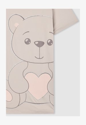 Camicetta beige chiaro con una grande grafica di un orsetto di peluche che tiene un cuore rosa contornato di glitter argentato sul davanti.