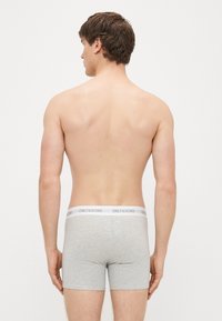 Harmaat puuvillaiset boksershortsit, joissa valkoinen elastinen vyötärönauha ja teksti "ONLY & SONS." Näkyvissä takaa.