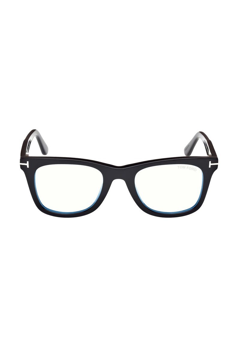 Zwarte, rechthoekige bril met dikke monturen en zilveren "T" logo's op elk montuur, heldere lenzen en "Tom Ford" branding op het rechterglas.
