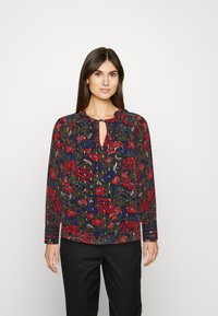 Blusa de manga longa estampada com base azul-marinho, rosas vermelhas e folhagem verde. Decote em forma de olho-chave e tecido franzido nos ombros.