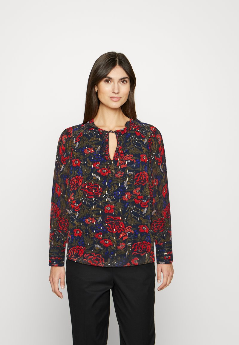 Blusa de manga longa estampada com base azul-marinho, rosas vermelhas e folhagem verde. Decote em forma de olho-chave e tecido franzido nos ombros.