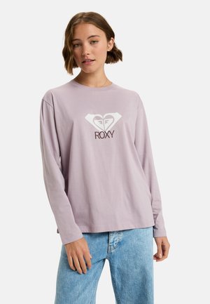 Licht lavendel langemouw t-shirt met een wit hartlogo en "ROXY" tekst. Gemaakt van zachte katoen met een relaxte pasvorm en ronde hals.