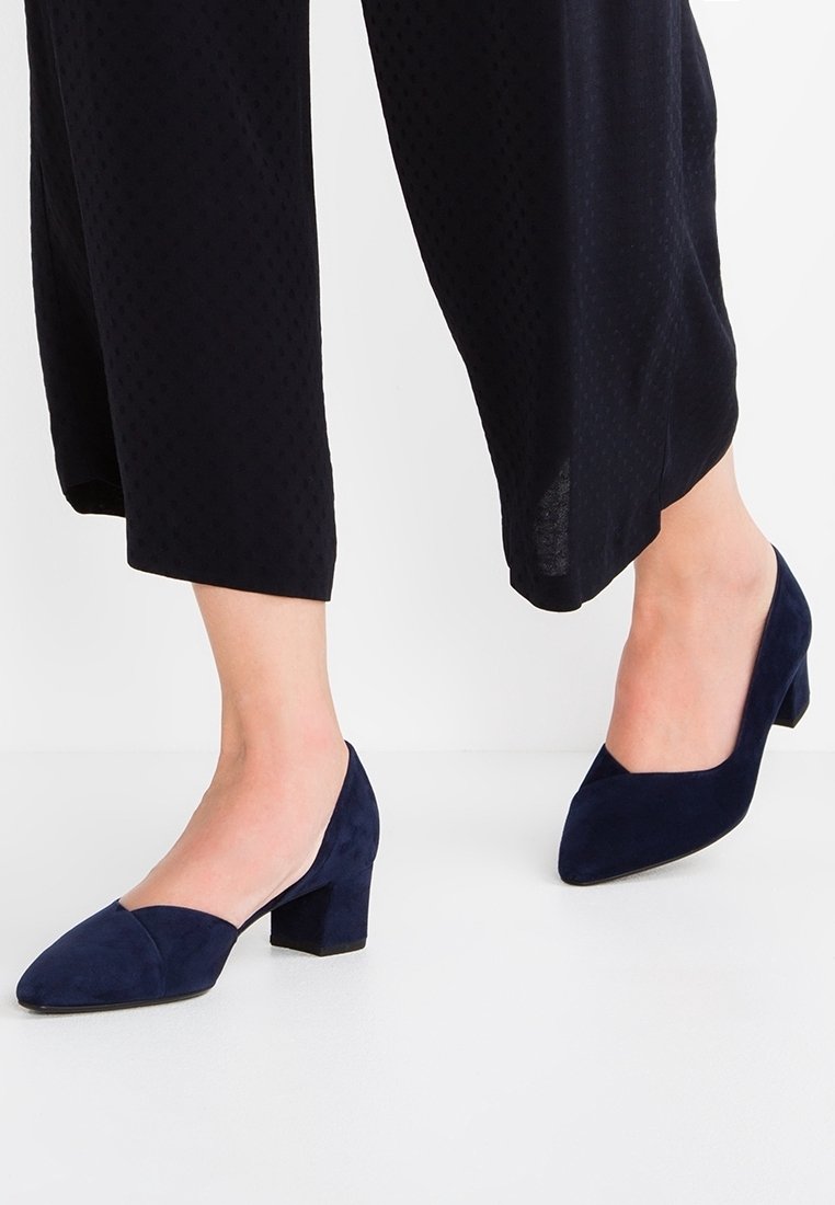 Escarpins en daim bleu marine avec un bout pointu et un talon bloc, présentant une texture lisse et un design minimaliste. Convient pour une tenue formelle.