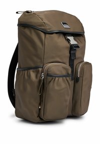 Ruskea nailonorelli mustilla yksityiskohdilla, etuläppä kiinnitetty metallisoljella, kaksi vetoketjullista etutaskua ja pehmustetut olkahihnat.